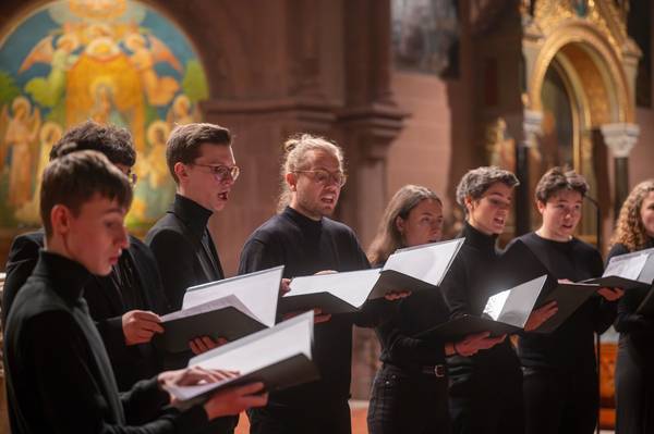 Chorsänger:innen singen mit geöffneten Mappen auf den Altarstufen der Freiburger Johanneskirche